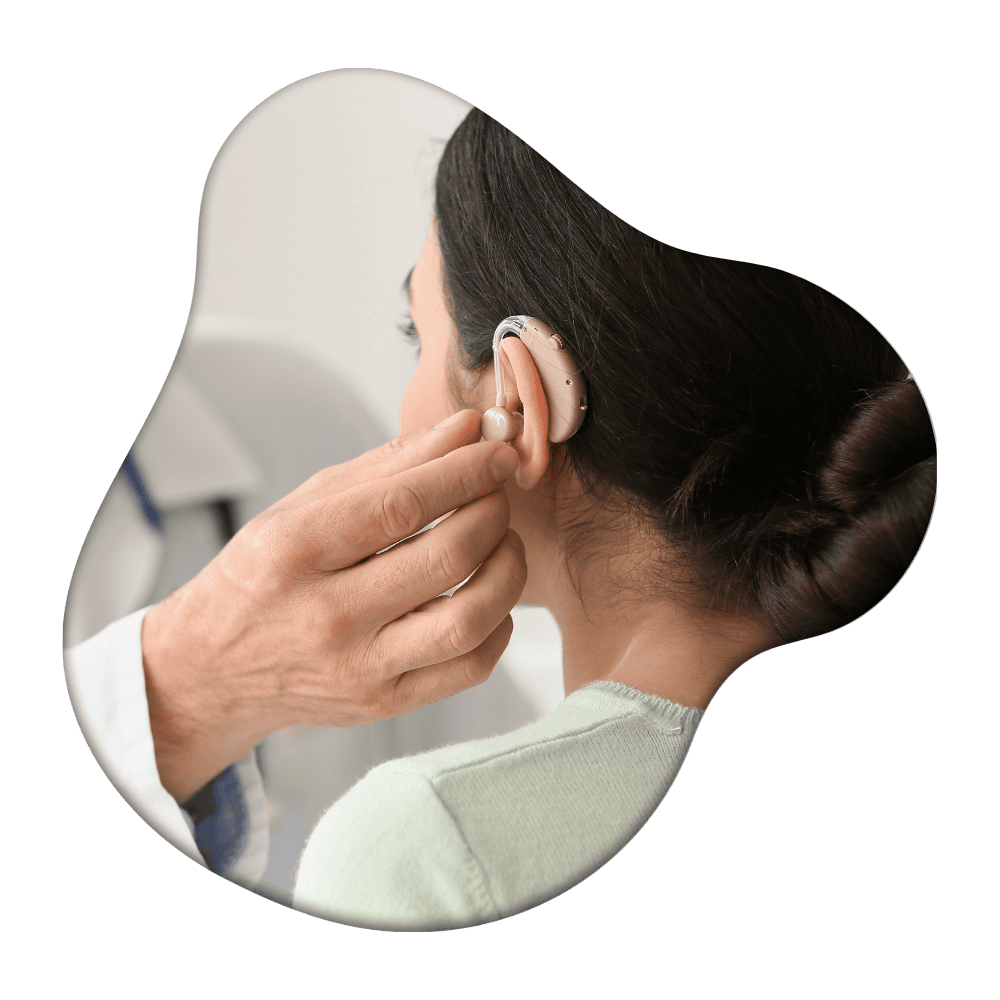 Healthcare professional fitting a hearing aid into a patient's ear during an audiological examination