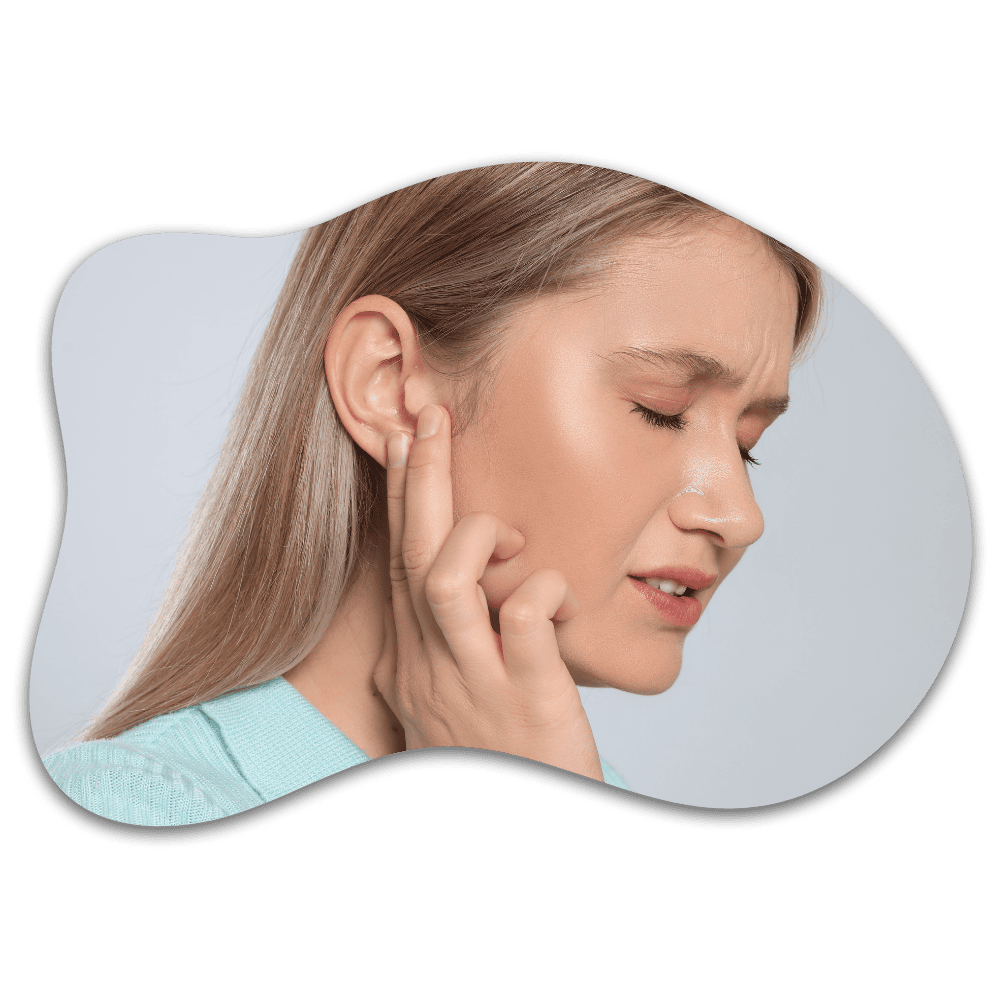 Woman touching her ear with eyes closed, appearing to experience ear pain or discomfort, wearing light blue top against gray background